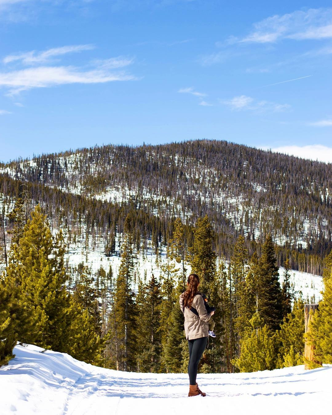 A woman standing in a snowy landscape, wearing winter clothing and surrounded by a blanket of fresh snow.