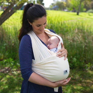 A woman holding a baby in a Baby K'tan carrier, demonstrating a comfortable and supportive position.