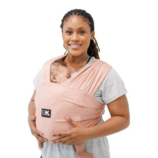 A women wearing a pink Baby K'tan Active Yoga Baby Carrier with a sleeping infant inside.