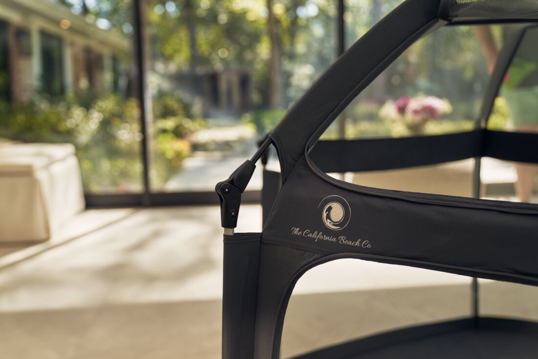 Close-up of a black chair with 'The California Beach Co.' logo, blurred indoor background