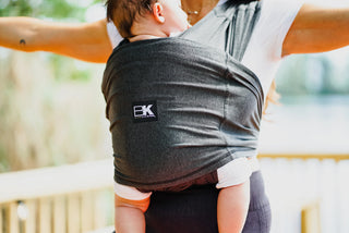 A woman with a baby in a Baby K'tan carrier, showcasing a loving bond as she holds her child comfortably.