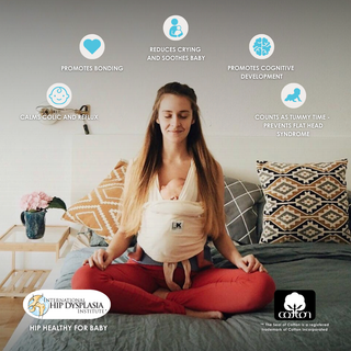 A woman in a Baby K'tan yoga sling, practicing meditation with a calm demeanor and relaxed posture.