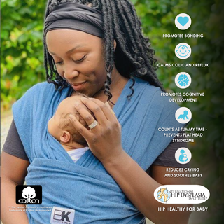 A woman holds her baby securely in a blue Baby K'tan wrap, showcasing a nurturing bond between mother and child.