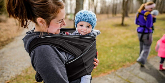 A woman with a baby in a carrier demonstrating a loving and supportive embrace between them