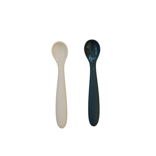 Two spoons, one beige and one black, on a white background