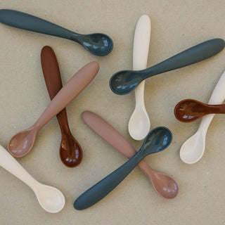 Set of colorful spoons on a beige background