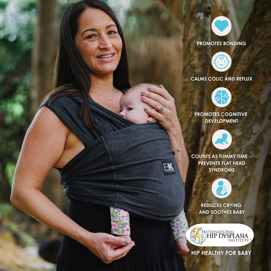 A woman wearing a Baby K'tan baby carrier, showcasing the product with the words "baby carrier" visible.