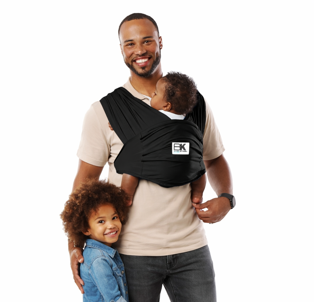 Man holding a child in a baby carrier with another child standing next to them on a white background