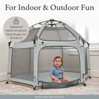 Child sitting inside a portable playpen with zipped mesh windows, suitable for indoor and outdoor use.