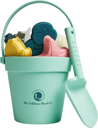 Children's sand toys including a bucket, spade, and molds on a green background.