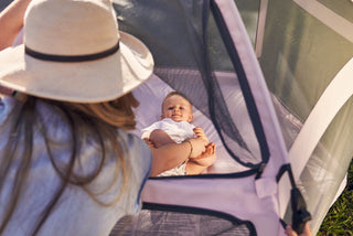Woman holding a baby in a stroller with a scenic background