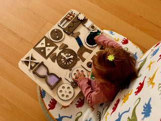 Child playing with a wooden puzzle on a colorful mat on a wooden floor