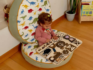 Child playing with a toy piano on a colorful dinosaur-patterned chair.