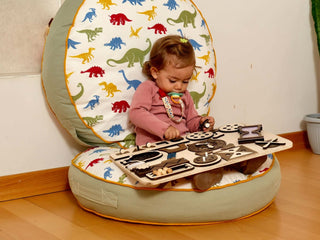 Child playing with a wooden toy on a colorful dinosaur-patterned chair.