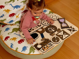 Child playing with a wooden toy on a mat with dinosaur patterns