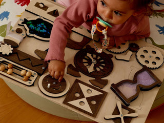 Child playing with a wooden toy set on a colorful mat