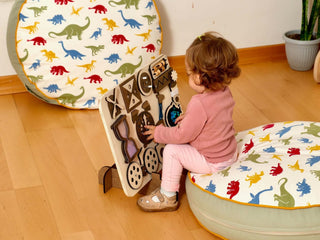 Child playing with a wooden puzzle on a colorful dinosaur-patterned mat.