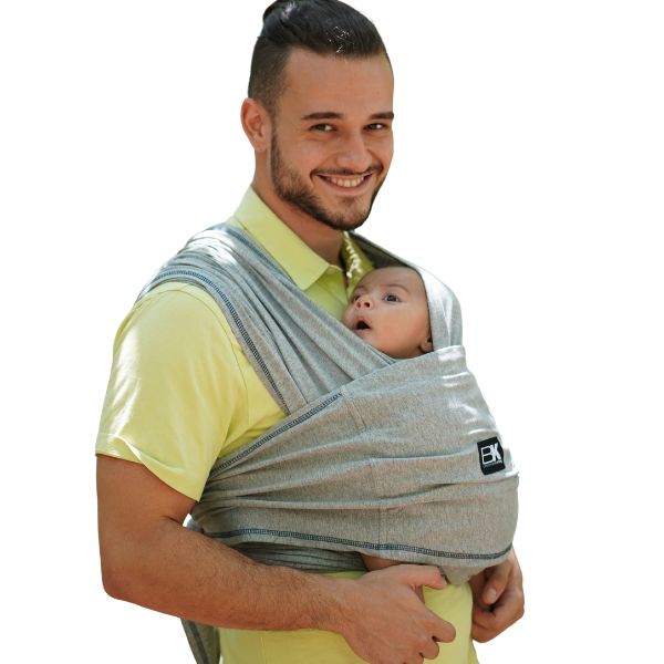 A man supports a baby in a Baby K'tan carrier, demonstrating a loving parent-child connection.