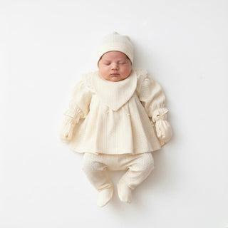Newborn baby in a cream outfit on a white background