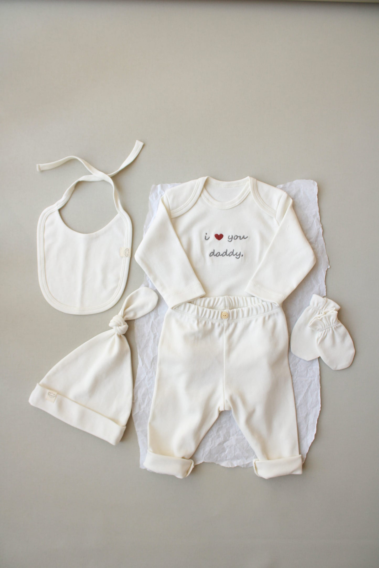 Baby outfit set with bib, romper, and booties on a neutral background