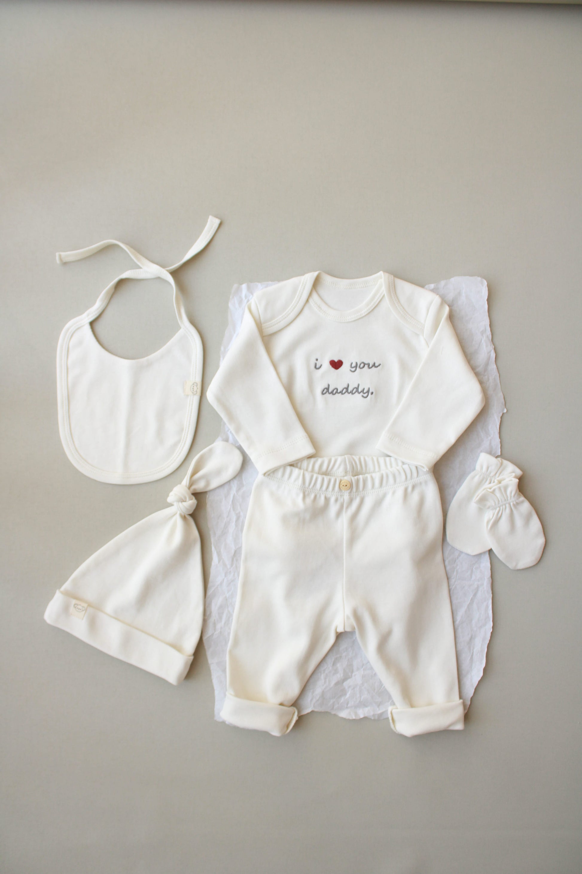 Baby outfit set with bib, romper, and booties on a neutral background
