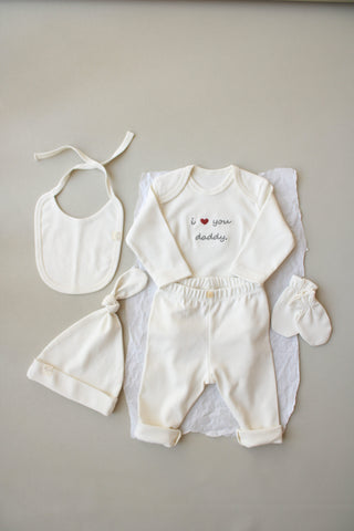 Baby outfit set with bib, romper, and booties on a neutral background