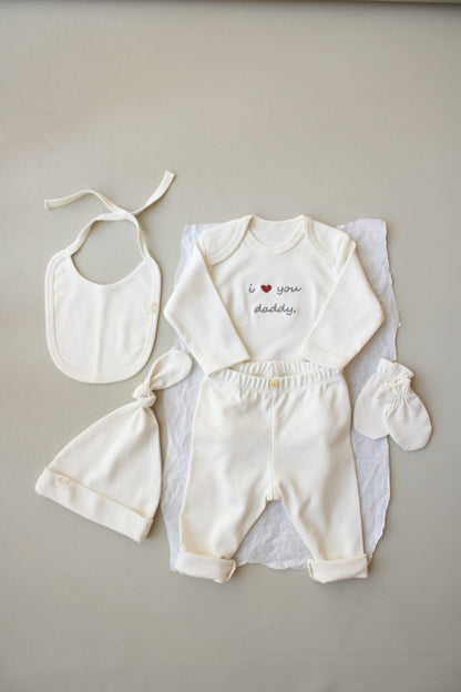 Baby outfit set with bib, romper, and booties on a neutral background
