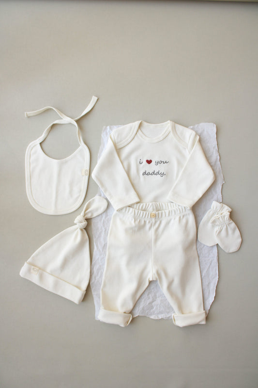 Baby outfit set with bib, romper, and booties on a neutral background