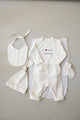 Baby outfit set with bib, romper, and booties on a neutral background