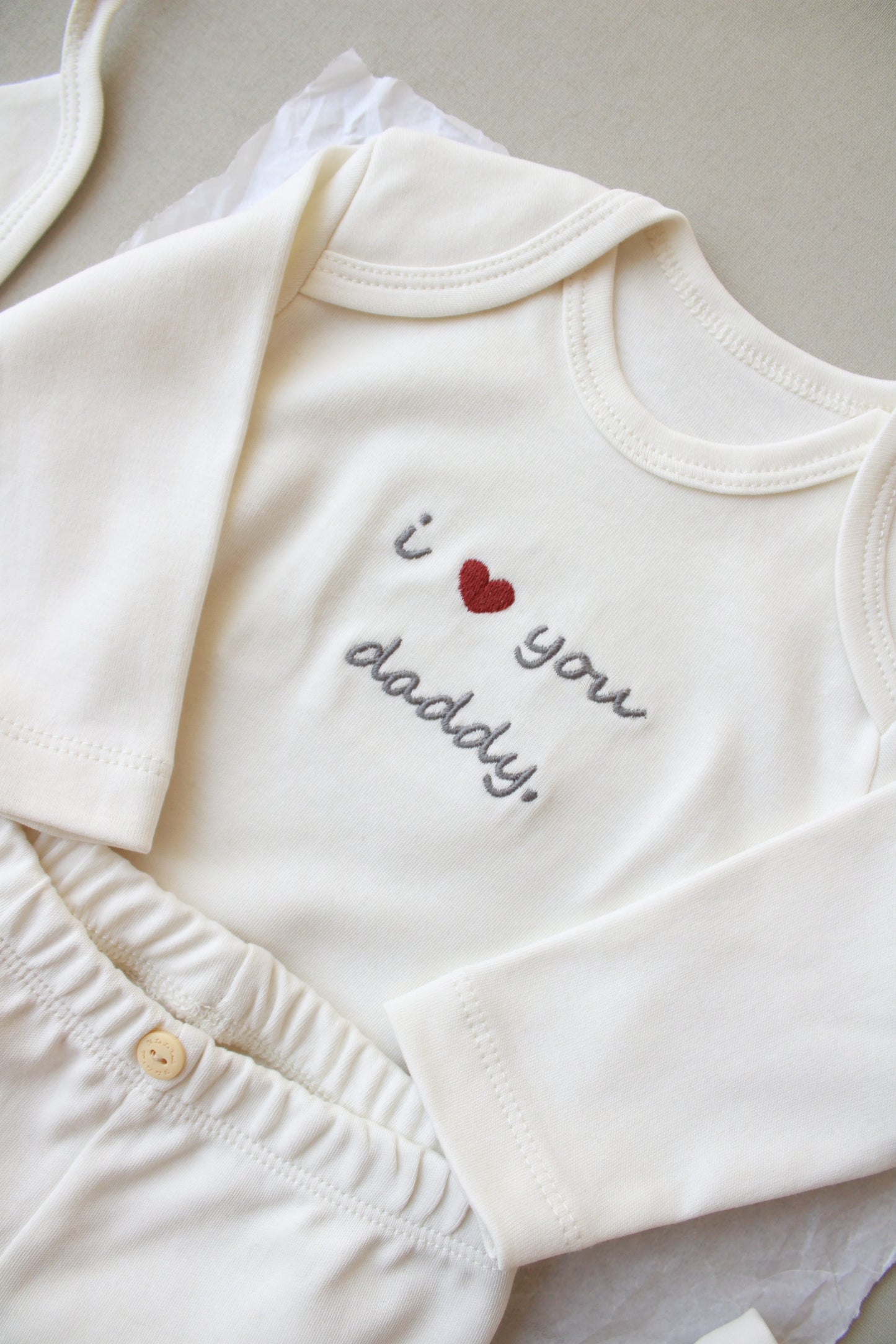 White baby romper with 'I love you daddy' text and heart design on a neutral background