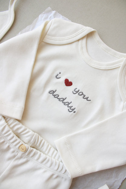 White baby romper with 'I love you daddy' text and heart design on a neutral background