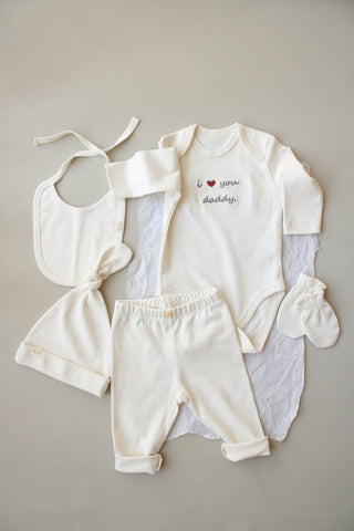 Baby clothing set with onesie, bib, pants, and socks on a neutral background