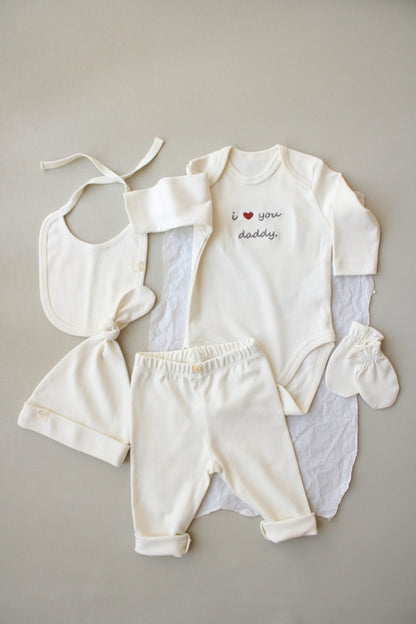 Baby clothing set with onesie, bib, pants, and socks on a neutral background