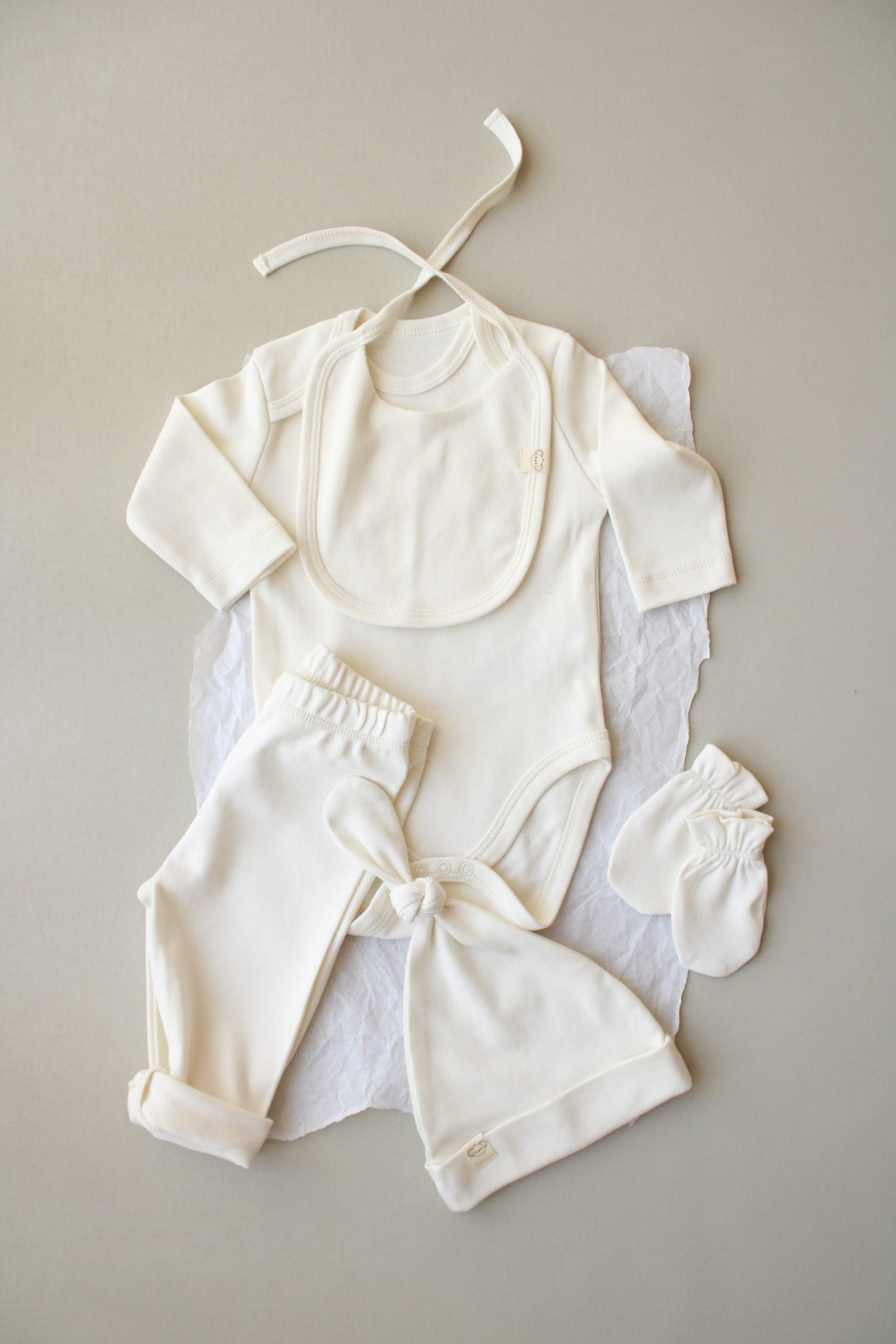 Set of white baby clothing on a gray background