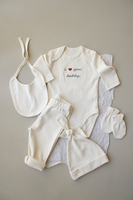 Baby outfit set with bib, romper, and booties on a neutral background