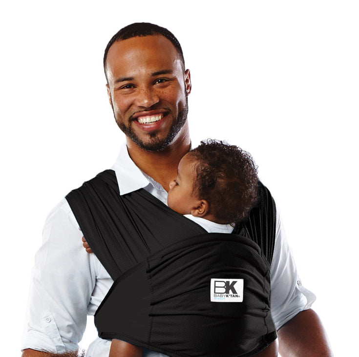 A man with a baby in a Baby K'tan carrier, reflecting warmth and care in their interaction.