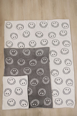 Set of three towels with smiley face patterns on a wooden surface