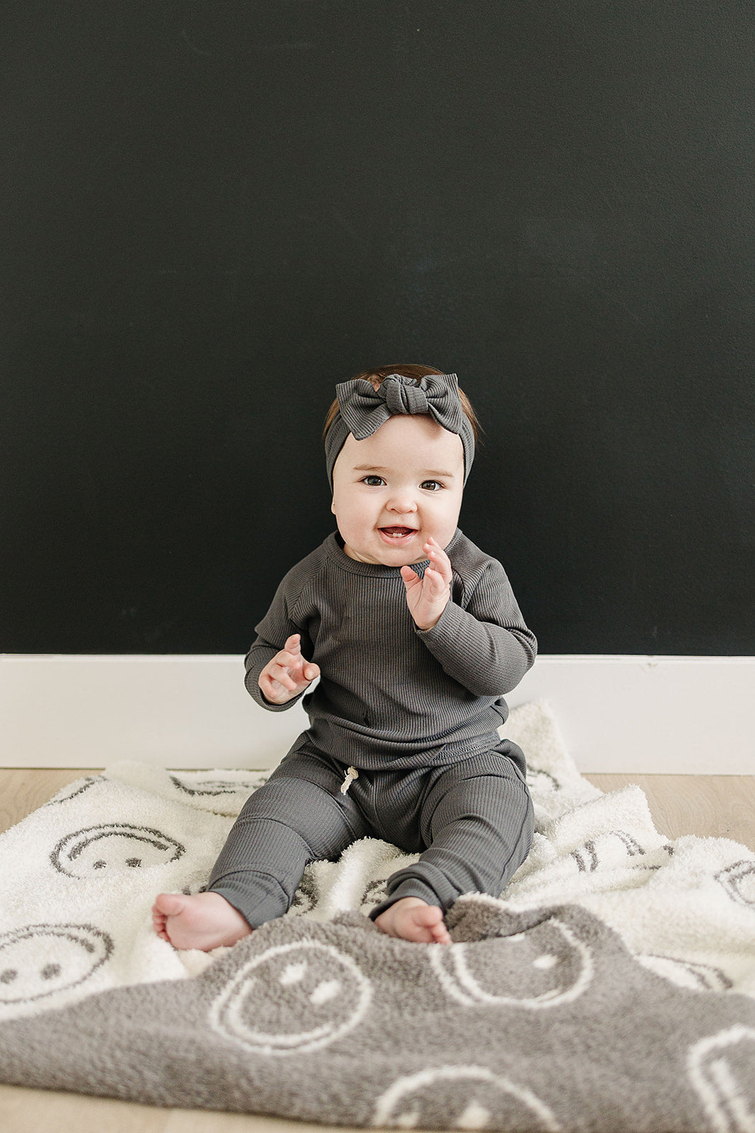 Baby sitting on a patterned rug with a black background