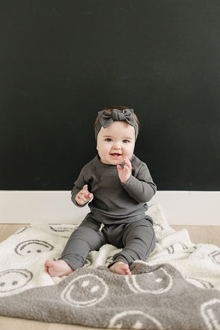 Baby sitting on a patterned rug with a black background
