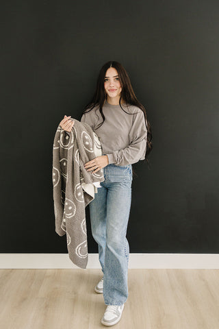 Woman holding a patterned blanket against a black wall