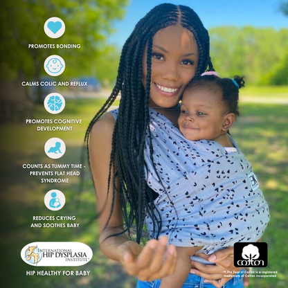 A woman holds her baby in a Baby K'tan sling, showcasing a comfortable and secure carrying option for infants.