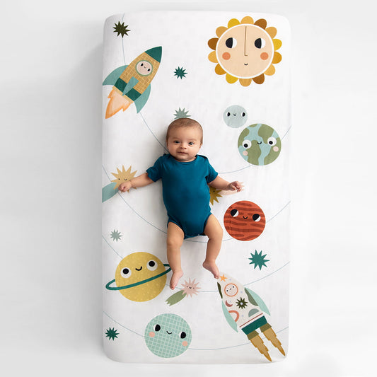 Baby lying on a crib sheet with space-themed illustrations