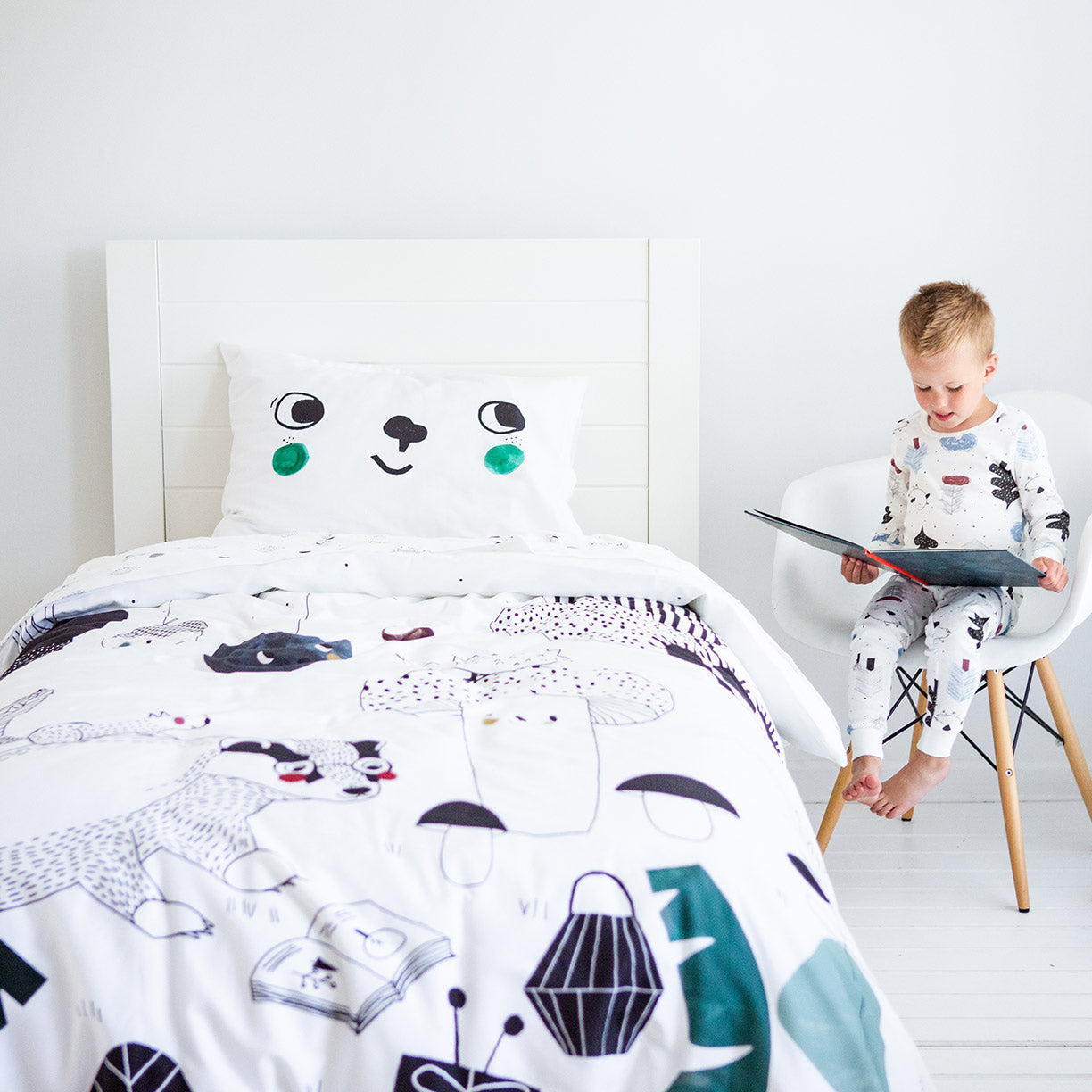 Child reading a book next to a bed with a cartoon character pillow