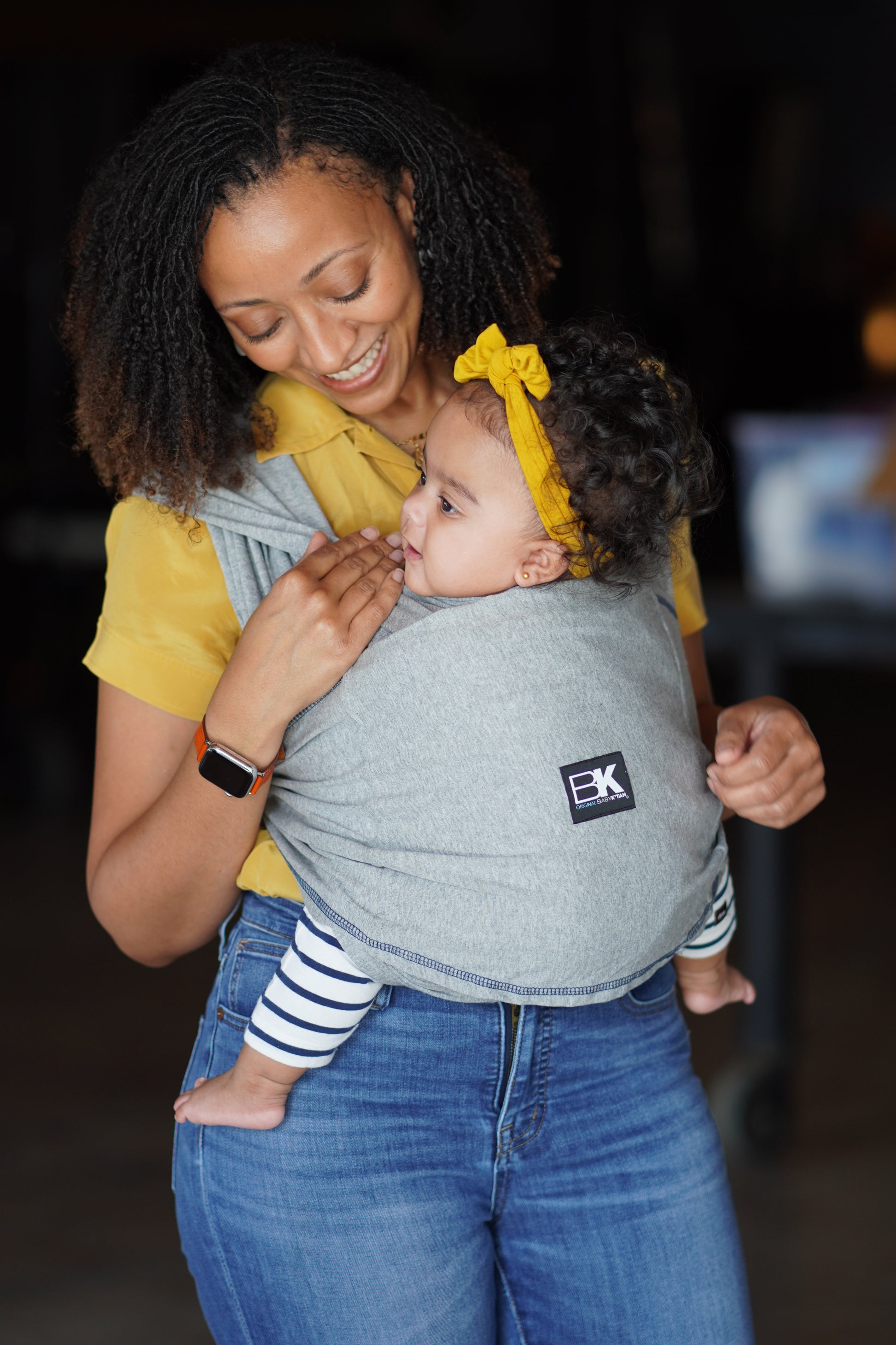 Woman holding a child in a sling with a blurred background