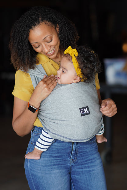 Woman holding a child in a sling with a blurred background