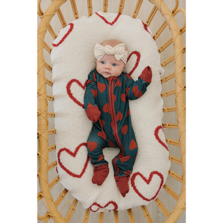 Baby in a heart-patterned crib with a white blanket