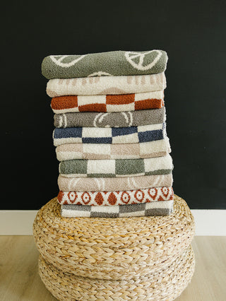 Stack of patterned towels on a woven basket with a black background