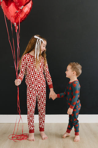 Two children in matching pajamas holding hands against a black background