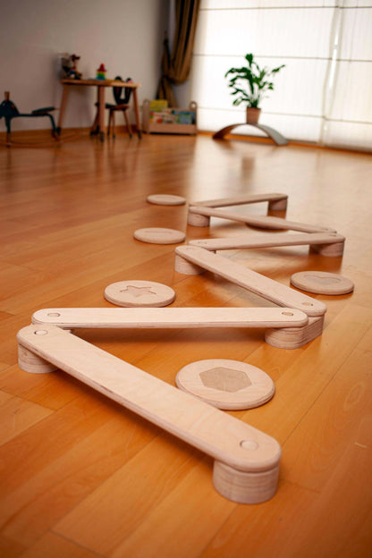 Wooden balance beams on a wooden floor in a room with a window and plant.