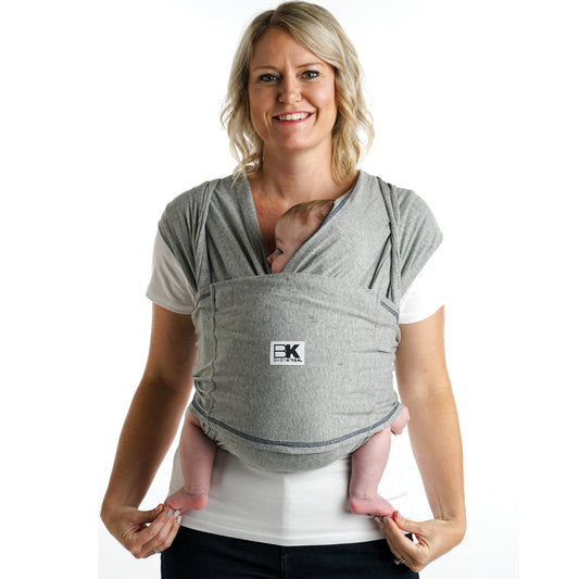 A person wearing a heather grey Baby K'tan original baby carrier with a sleeping infant inside.